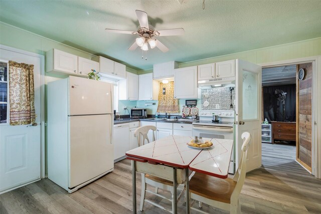 kitchen with decorative backsplash, white cabinetry, white appliances, and light wood-type flooring