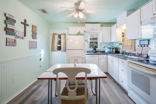 kitchen with sink, white cabinets, white appliances, and hardwood / wood-style flooring