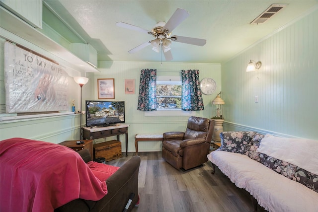 living room with crown molding, ceiling fan, and wood-type flooring