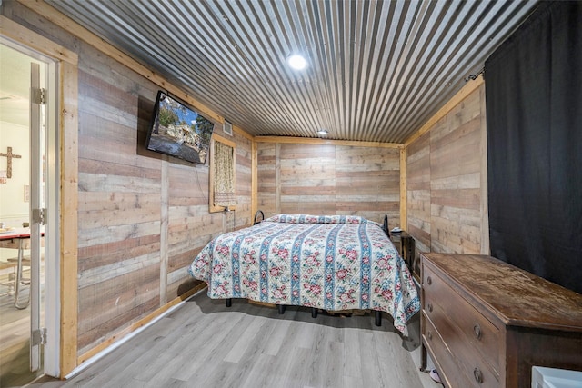 bedroom featuring light hardwood / wood-style flooring and wooden walls