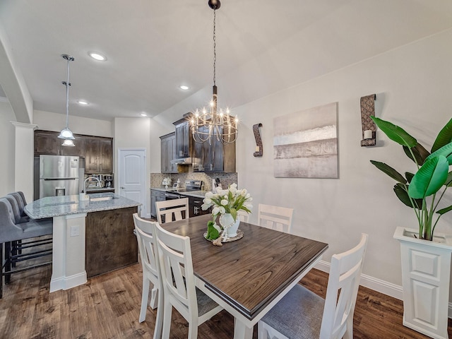 dining space with dark hardwood / wood-style floors, a notable chandelier, and sink