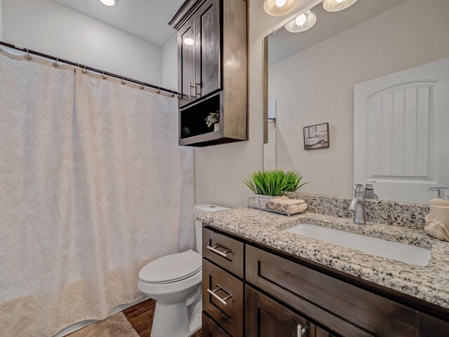 bathroom with toilet, vanity, and hardwood / wood-style flooring