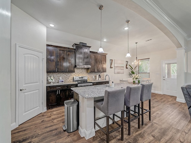 kitchen with dark brown cabinets, dark hardwood / wood-style flooring, a kitchen island with sink, and stainless steel range with electric cooktop