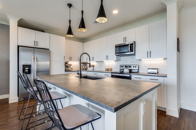 kitchen with a kitchen island with sink, sink, white cabinets, and appliances with stainless steel finishes