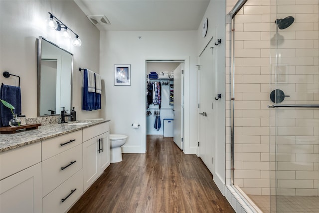 bathroom with hardwood / wood-style floors, vanity, toilet, and a shower with shower door