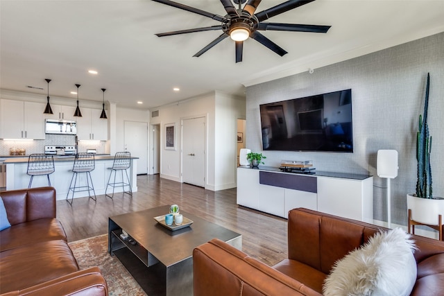 living room featuring dark hardwood / wood-style floors, ceiling fan, and crown molding