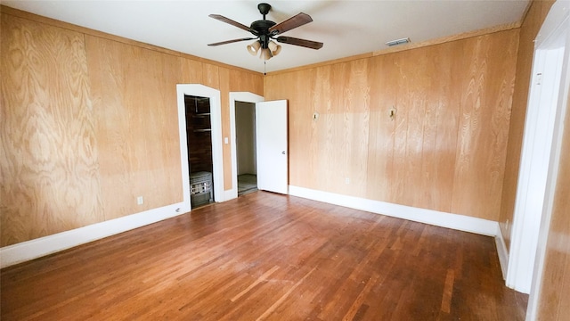 spare room with hardwood / wood-style flooring, ceiling fan, and wood walls