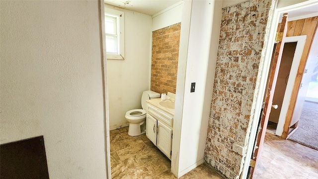 bathroom featuring vanity, brick wall, and toilet