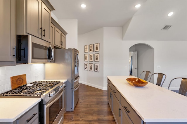 kitchen with a center island, stainless steel appliances, dark wood-type flooring, and gray cabinetry