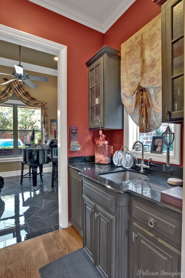 kitchen featuring sink, ornamental molding, dark stone counters, and ceiling fan