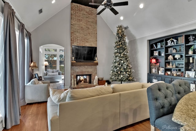 living room featuring ceiling fan, high vaulted ceiling, a fireplace, and light hardwood / wood-style floors