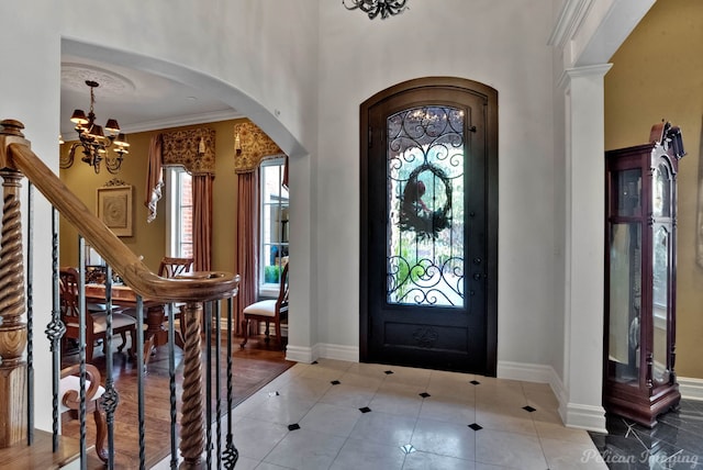 tiled entrance foyer with crown molding and a chandelier