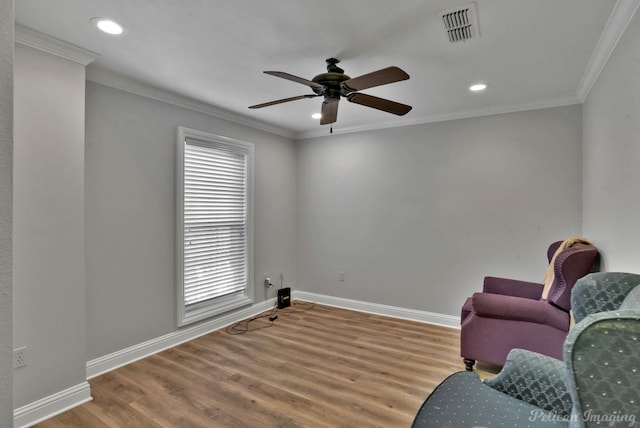 living area featuring hardwood / wood-style floors, ornamental molding, and ceiling fan