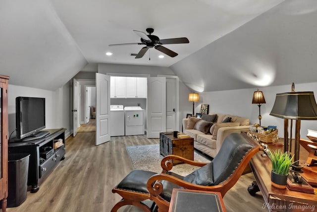 living room featuring vaulted ceiling, washer and clothes dryer, and light hardwood / wood-style flooring