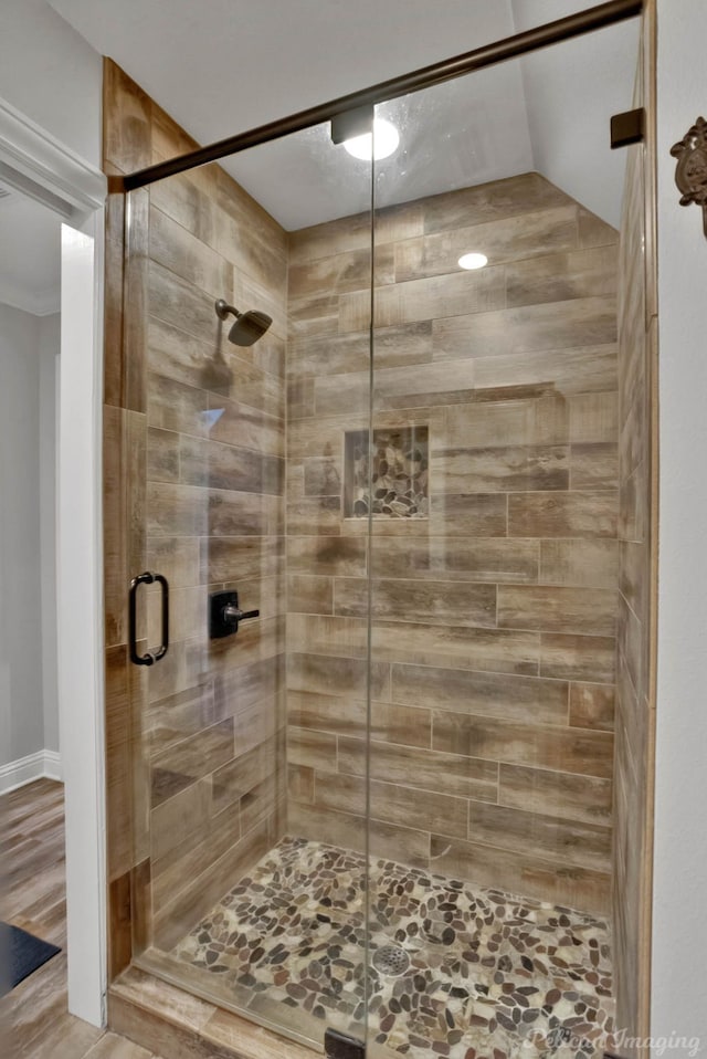 bathroom with hardwood / wood-style flooring and a shower with shower door