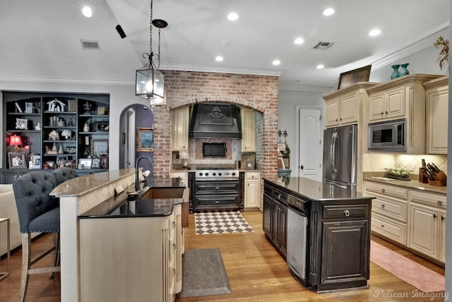 kitchen with sink, hanging light fixtures, stainless steel appliances, a center island, and cream cabinets