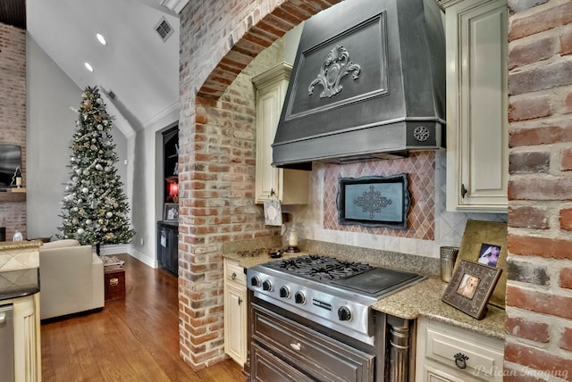 kitchen with light hardwood / wood-style floors, light stone countertops, custom range hood, stainless steel gas cooktop, and cream cabinetry