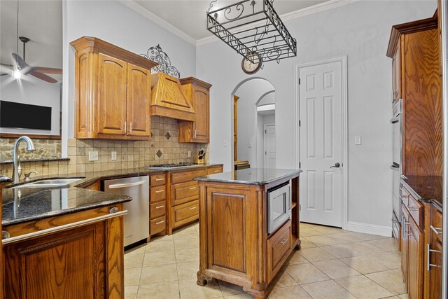 kitchen with sink, a kitchen island, stainless steel appliances, and light tile patterned floors