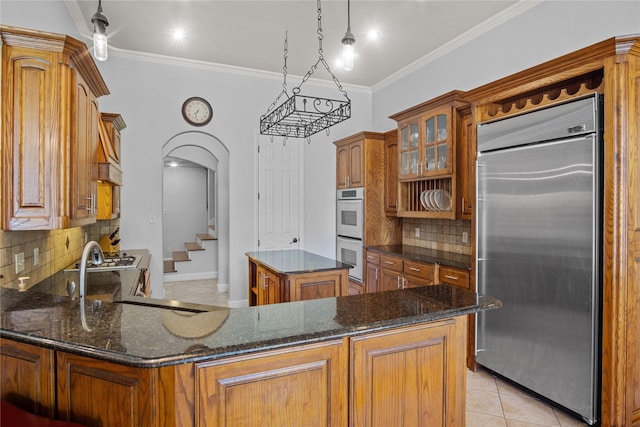 kitchen with white double oven, backsplash, crown molding, stainless steel built in fridge, and a kitchen island