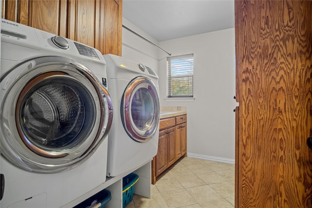 laundry area featuring washer and clothes dryer, light tile patterned floors, and cabinets