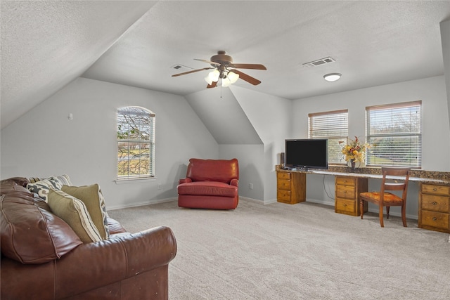 carpeted office space with a textured ceiling, vaulted ceiling, and ceiling fan