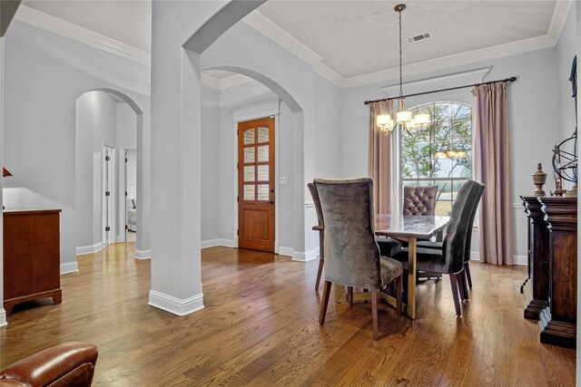 dining space with a chandelier, crown molding, and light hardwood / wood-style floors