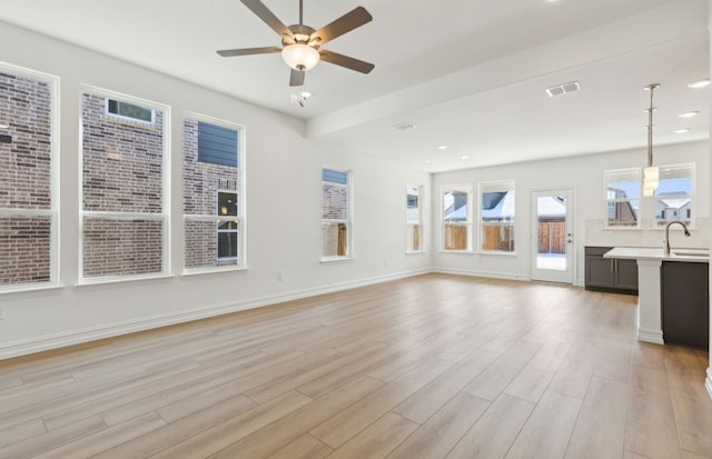 unfurnished living room with ceiling fan, sink, and light wood-type flooring