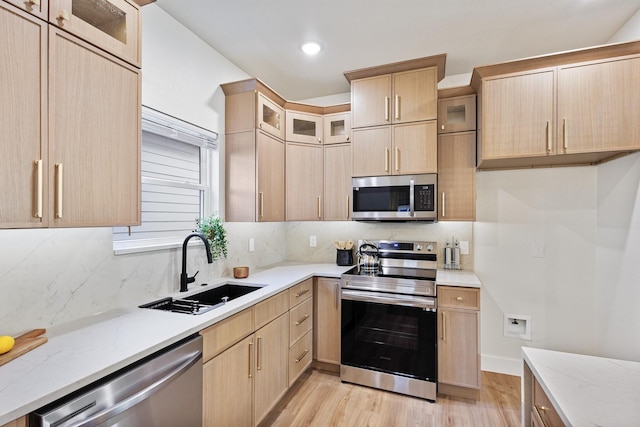 1724 S Hughes Ave, Fort Worth, TX 76105 - kitchen featuring appliances with stainless steel finishes, light brown cabinets, light wood finished floors, tasteful backsplash, and glass insert cabinets