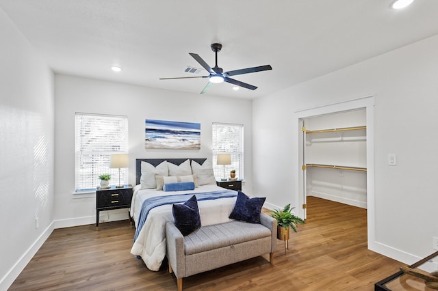 bedroom with ceiling fan, a walk in closet, wood-type flooring, and a closet