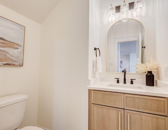 bathroom featuring vanity, toilet, and vaulted ceiling