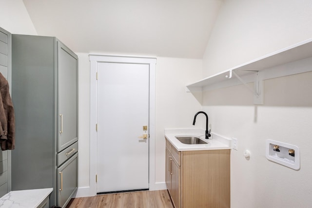 laundry area with washer hookup, sink, light hardwood / wood-style floors, and cabinets