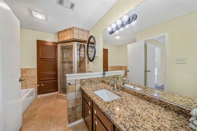 bathroom featuring tile patterned floors, vanity, a textured ceiling, tile walls, and shower with separate bathtub