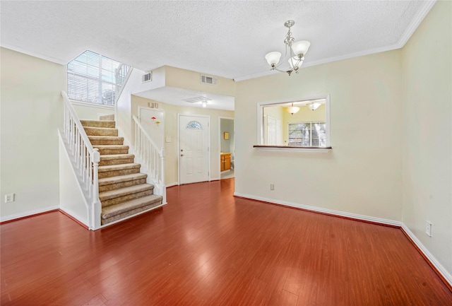 entryway featuring an inviting chandelier, ornamental molding, a textured ceiling, and hardwood / wood-style flooring