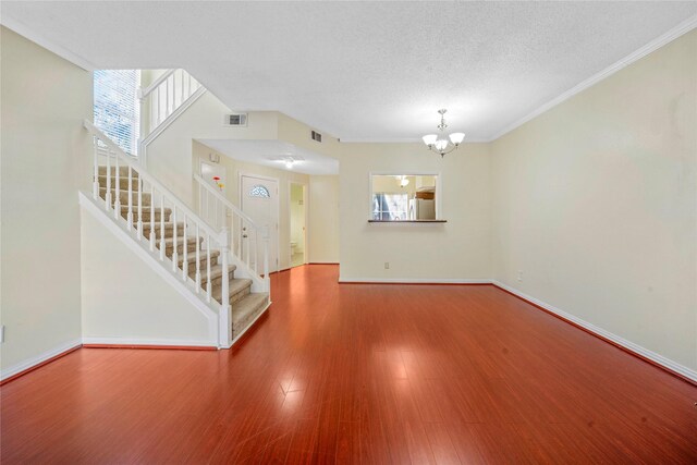 unfurnished living room featuring crown molding, hardwood / wood-style floors, a textured ceiling, and a notable chandelier