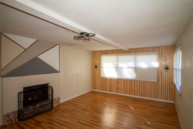 unfurnished living room with hardwood / wood-style floors, a brick fireplace, and a textured ceiling