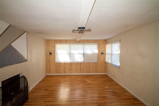 unfurnished living room with hardwood / wood-style flooring, a fireplace, a textured ceiling, and ceiling fan