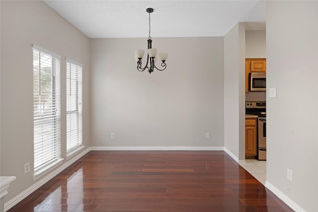 unfurnished dining area with a notable chandelier, plenty of natural light, and light wood-type flooring