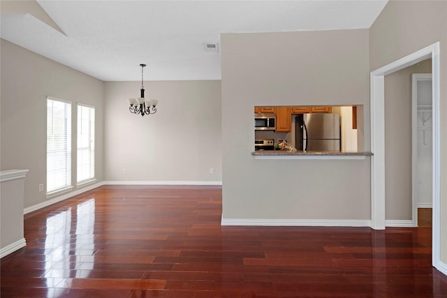 unfurnished living room with dark wood-type flooring and a notable chandelier