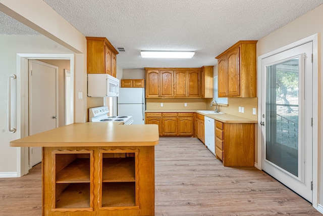 kitchen featuring a textured ceiling, light hardwood / wood-style flooring, white appliances, and sink