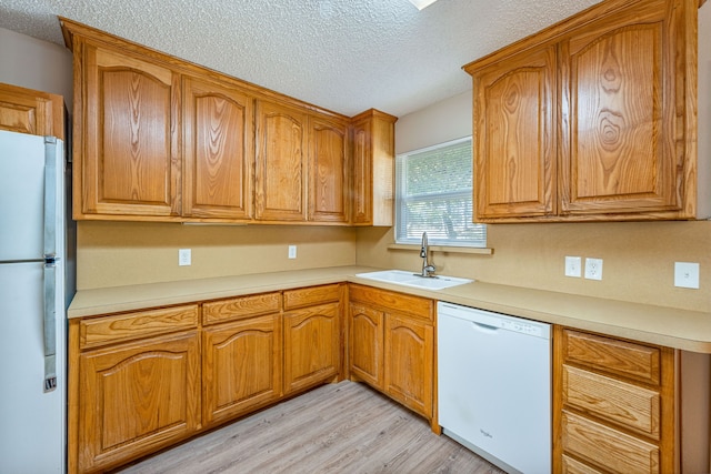 kitchen featuring a textured ceiling, light wood-type flooring, white appliances, and sink