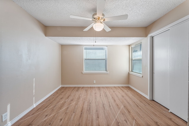 unfurnished bedroom featuring ceiling fan, a closet, a textured ceiling, and light wood-type flooring