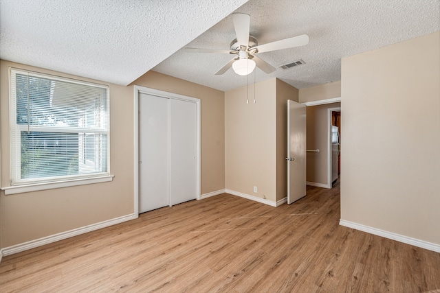 unfurnished bedroom with ceiling fan, light hardwood / wood-style floors, a textured ceiling, and a closet