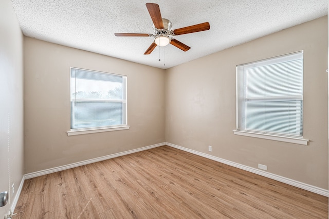 spare room with a textured ceiling, light wood-type flooring, and ceiling fan