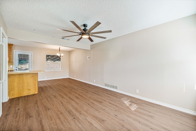 interior space with hardwood / wood-style floors, ceiling fan with notable chandelier, and a textured ceiling