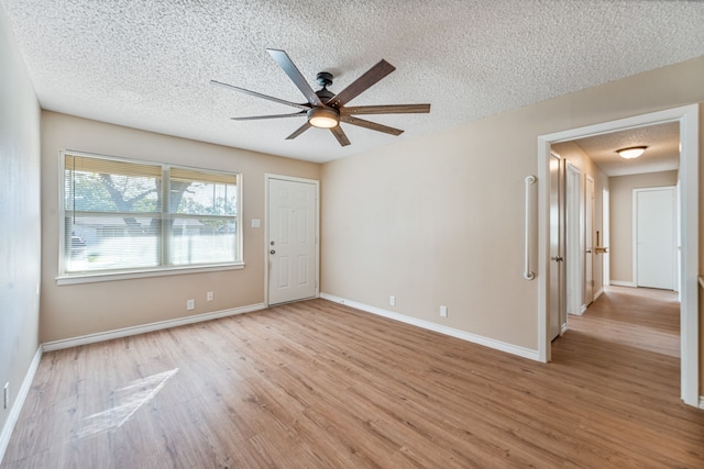 empty room with ceiling fan, light wood-type flooring, and a textured ceiling