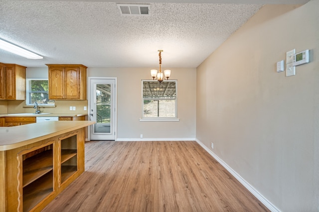 kitchen featuring plenty of natural light, light hardwood / wood-style floors, hanging light fixtures, and an inviting chandelier