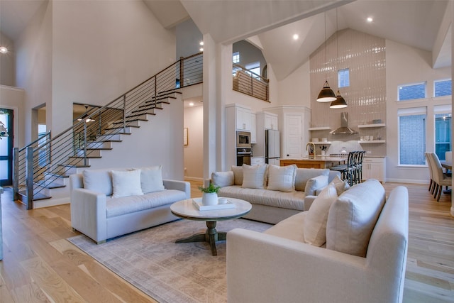 living room featuring a wealth of natural light, light hardwood / wood-style flooring, high vaulted ceiling, and sink