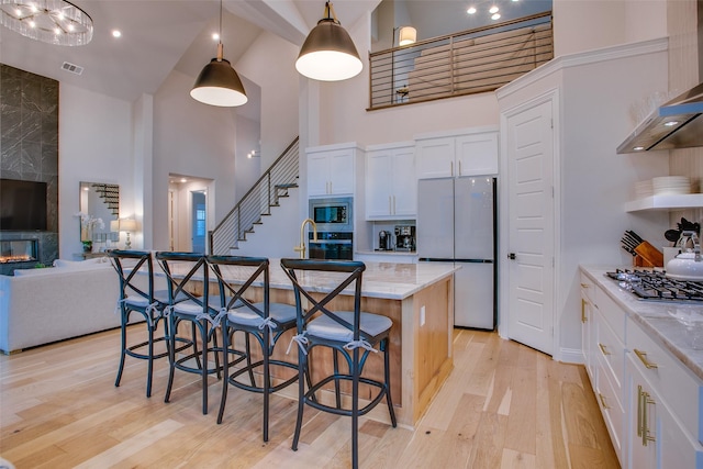 kitchen featuring white cabinets, hanging light fixtures, high vaulted ceiling, and stainless steel appliances