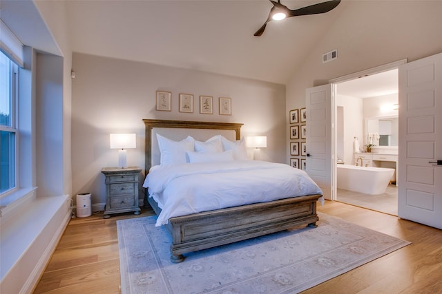 bedroom with ceiling fan, light hardwood / wood-style flooring, high vaulted ceiling, and ensuite bathroom