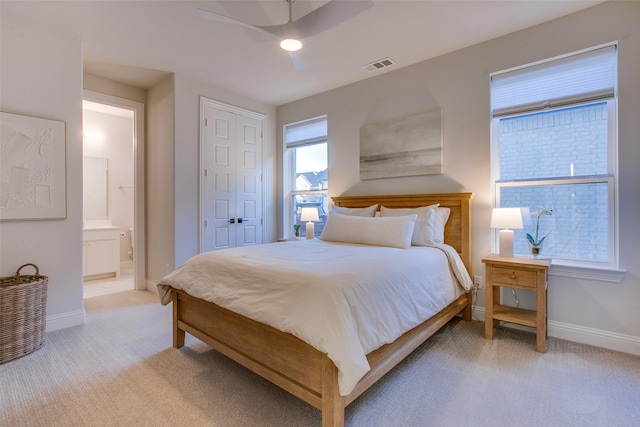 bedroom featuring ceiling fan, light carpet, and ensuite bath